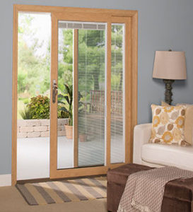 Sliding Glass Doors With Natural Wood Framing Open Out Onto a Sunny Patio